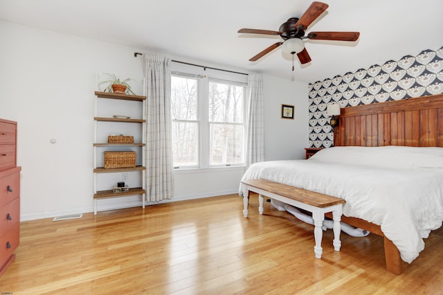 bedroom with light wood-style floors, visible vents, baseboards, and wallpapered walls