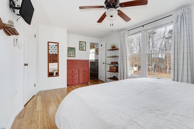 bedroom with ceiling fan, baseboards, wood finished floors, and ensuite bathroom