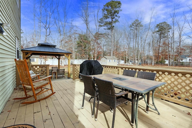 wooden terrace with outdoor dining space, fence, area for grilling, and a gazebo