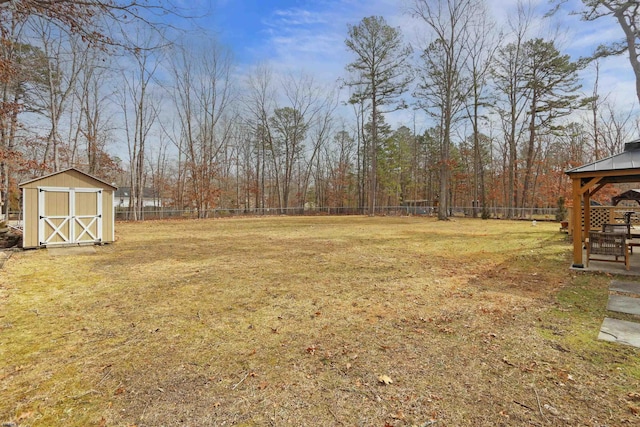 view of yard featuring a gazebo, a fenced backyard, an outdoor structure, and a storage shed