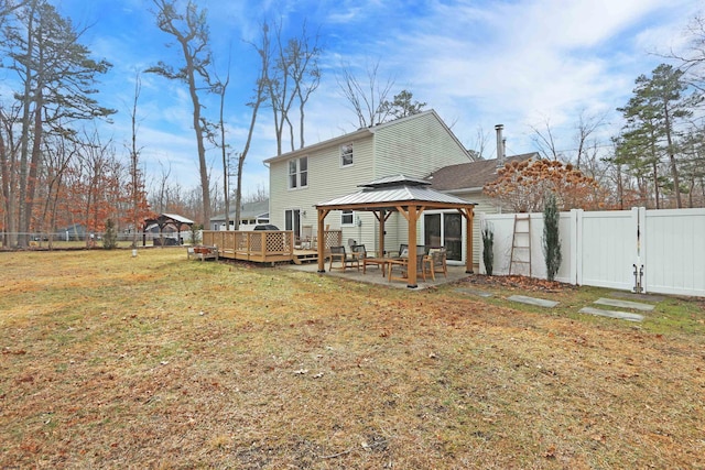 rear view of house with a gate, a fenced backyard, a yard, and a gazebo