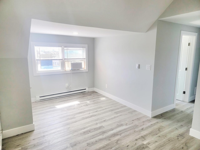 empty room featuring lofted ceiling, a baseboard radiator, light wood-style flooring, and baseboards