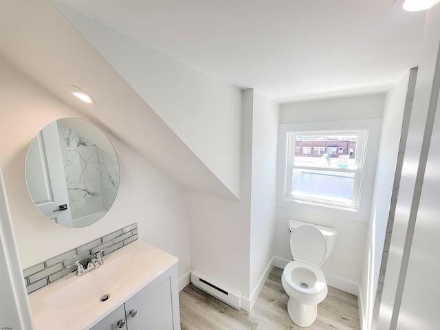 bathroom with a baseboard radiator, toilet, wood finished floors, vanity, and baseboards