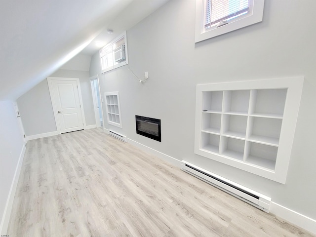 unfurnished living room with a baseboard heating unit, a glass covered fireplace, light wood-type flooring, and vaulted ceiling