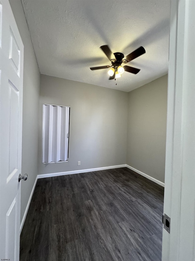 empty room with a textured ceiling, ceiling fan, dark wood finished floors, and baseboards