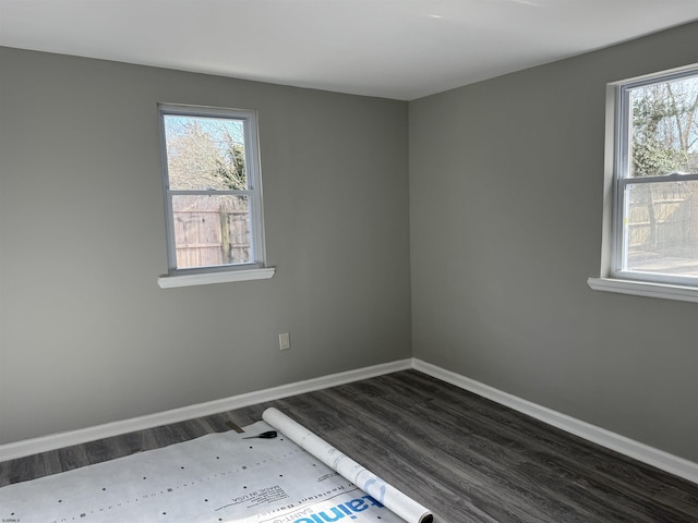 empty room featuring dark wood-style flooring, plenty of natural light, and baseboards