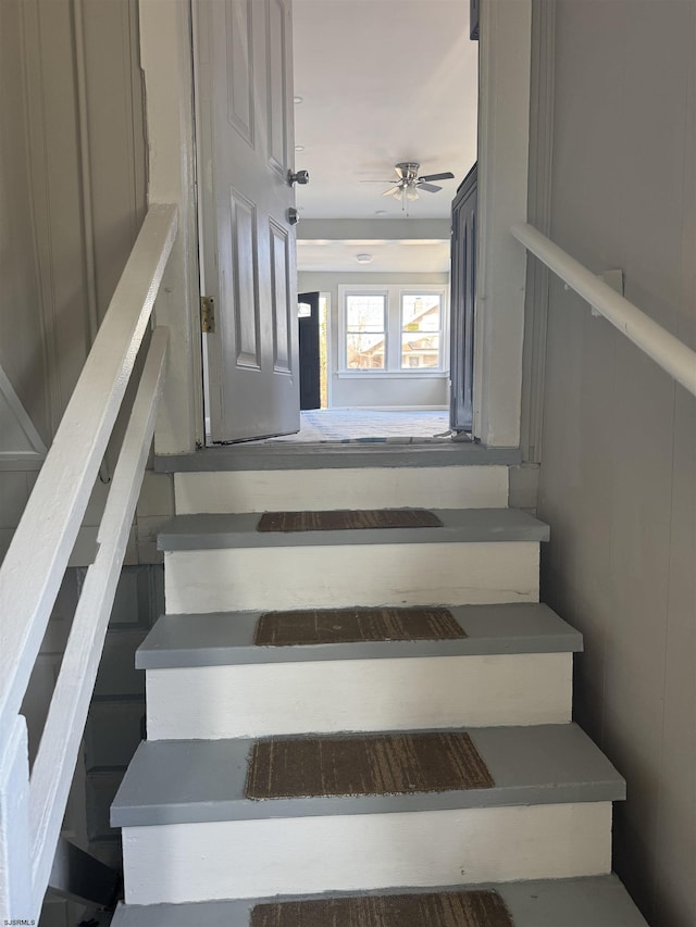 staircase featuring ceiling fan