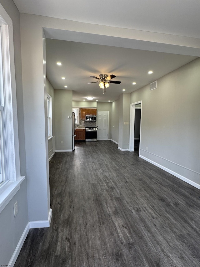 unfurnished living room with baseboards, visible vents, ceiling fan, dark wood-style flooring, and recessed lighting