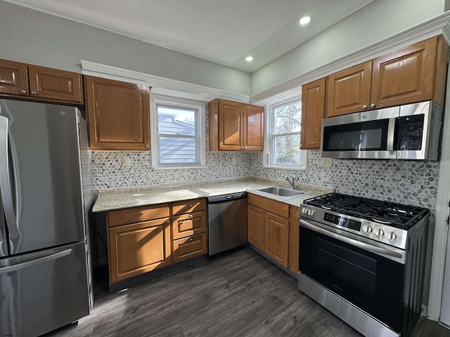 kitchen with dark wood-style floors, light countertops, backsplash, appliances with stainless steel finishes, and a sink