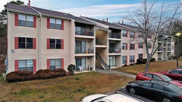 view of property with uncovered parking, stairway, and cooling unit