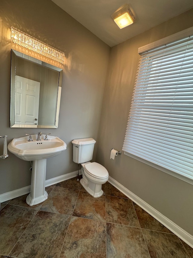 bathroom featuring a sink, toilet, and baseboards