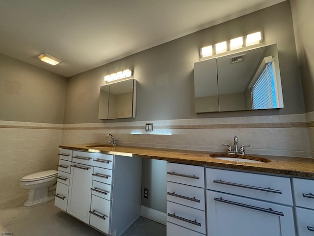 bathroom featuring double vanity, tile walls, visible vents, and a sink