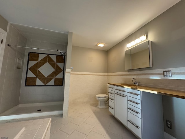 full bathroom with toilet, a wainscoted wall, vanity, tile walls, and tile patterned floors