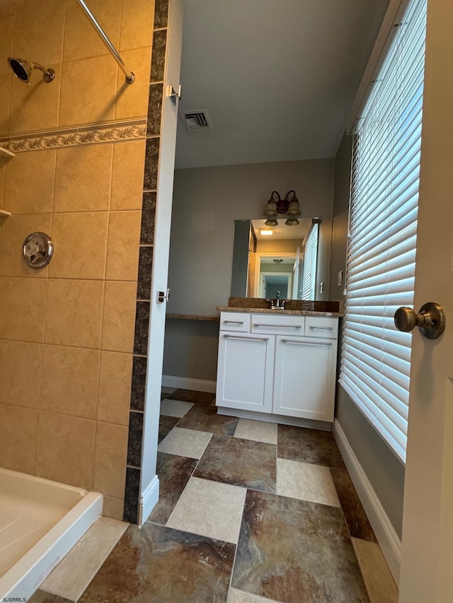 full bathroom with a stall shower, vanity, visible vents, and baseboards