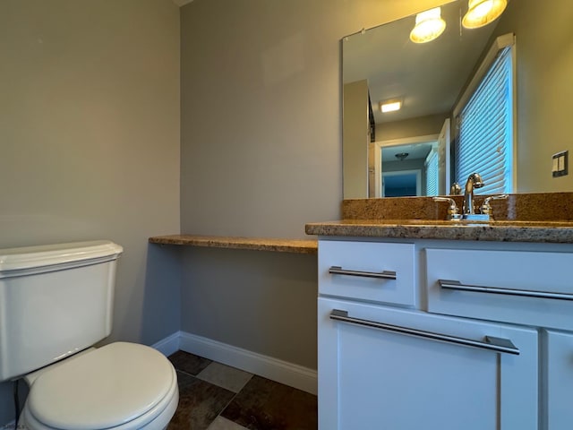 bathroom with toilet, baseboards, and vanity