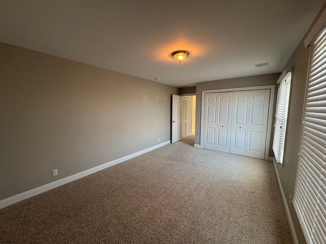 unfurnished bedroom featuring carpet floors, a closet, visible vents, and baseboards