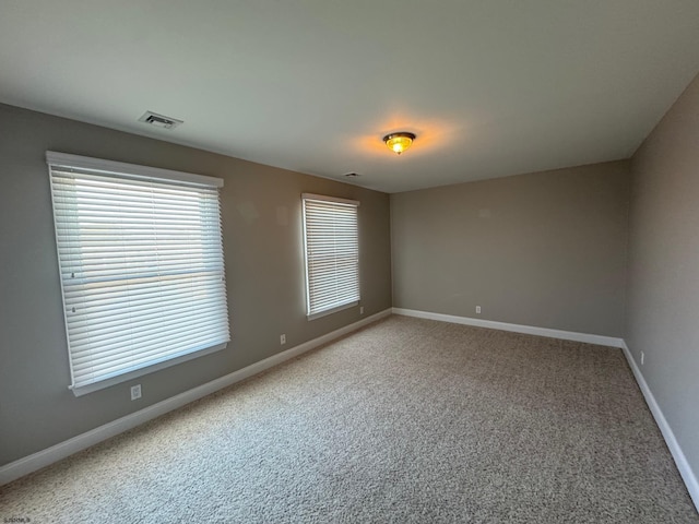 unfurnished room featuring carpet flooring, visible vents, and baseboards