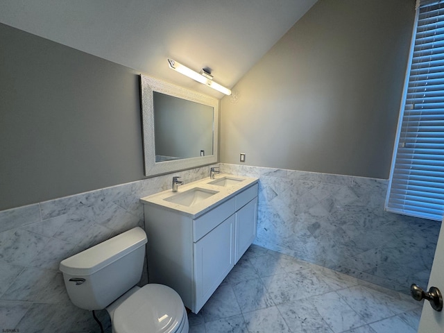 bathroom featuring vaulted ceiling, a wainscoted wall, a sink, and marble finish floor