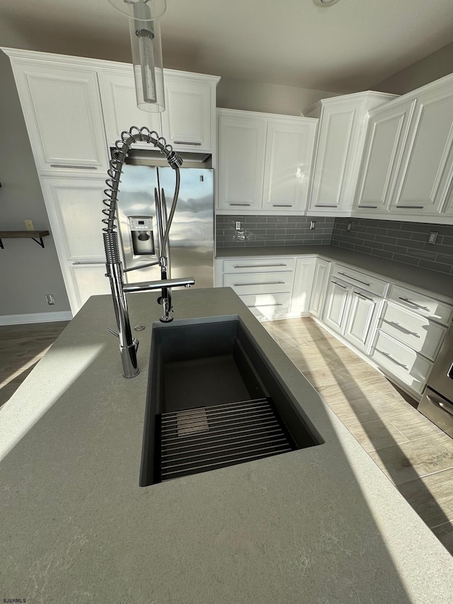 kitchen featuring a sink, white cabinets, decorative backsplash, and stainless steel fridge with ice dispenser