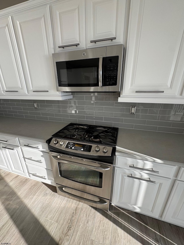 kitchen with stainless steel appliances, decorative backsplash, light countertops, and white cabinets