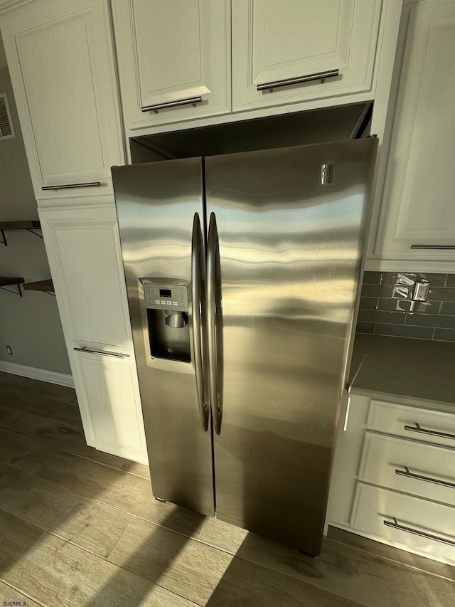 kitchen with visible vents, decorative backsplash, light wood-style floors, white cabinets, and stainless steel fridge with ice dispenser