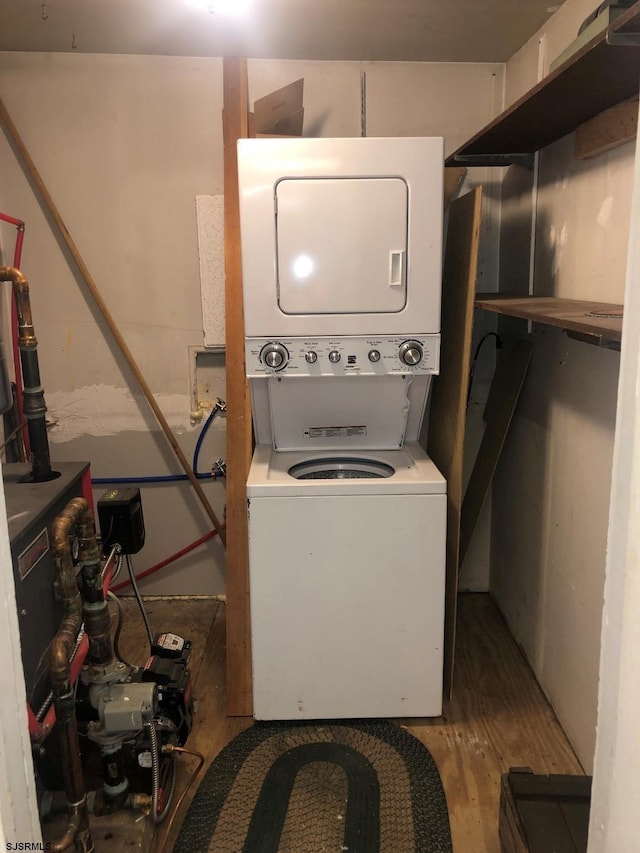 washroom with laundry area, wood finished floors, and stacked washer and clothes dryer