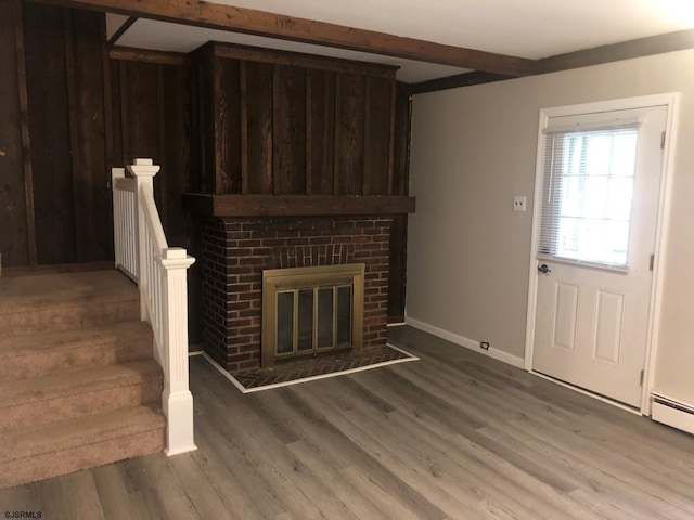 unfurnished living room featuring a fireplace, wood finished floors, baseboards, stairs, and beam ceiling