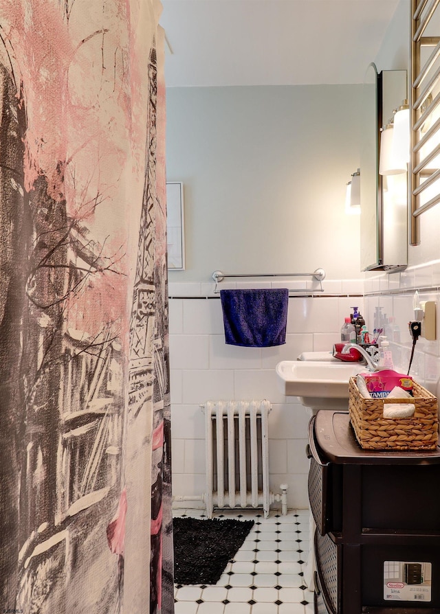 full bathroom featuring radiator, a wainscoted wall, tile walls, and a sink