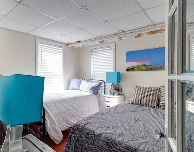 bedroom with a drop ceiling and wood finished floors