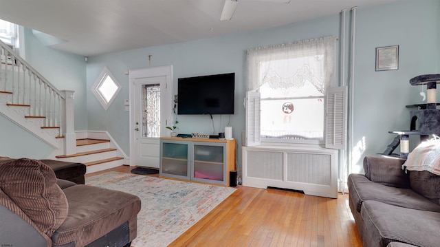 living area with a healthy amount of sunlight, radiator, stairs, and wood finished floors