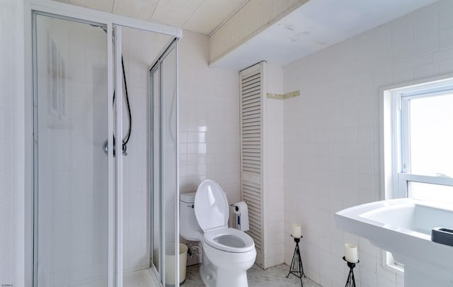 bathroom featuring toilet, a shower stall, a closet, and tile walls