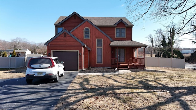 view of front of house with a garage, covered porch, driveway, and fence