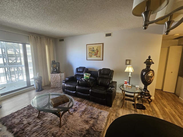 living area with a textured ceiling, wood finished floors, and visible vents