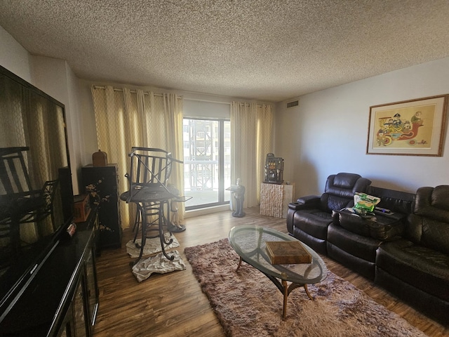 living area with a textured ceiling, wood finished floors, and visible vents