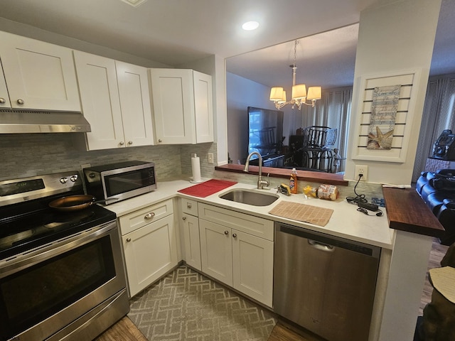 kitchen with stainless steel appliances, a sink, white cabinets, and under cabinet range hood