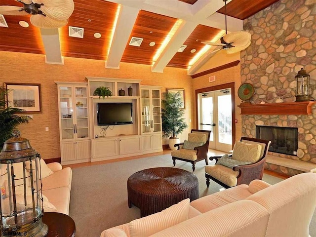 living area with wooden ceiling, a fireplace, a ceiling fan, french doors, and beamed ceiling