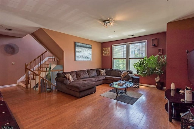 living room with stairway, wood finished floors, visible vents, and baseboards