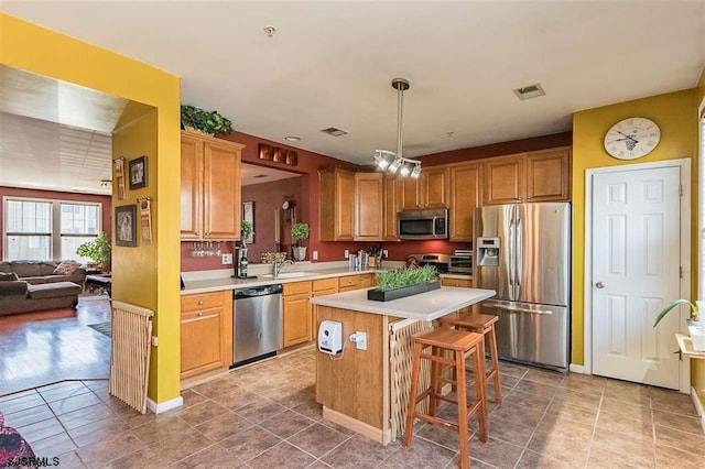 kitchen featuring a center island, pendant lighting, light countertops, visible vents, and appliances with stainless steel finishes