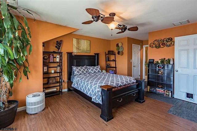 bedroom featuring visible vents, ceiling fan, baseboards, and wood finished floors