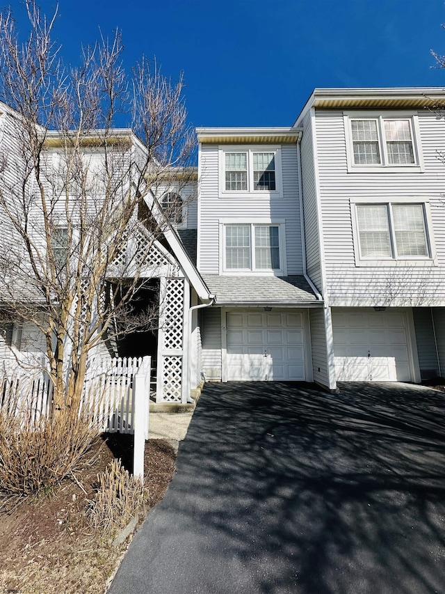 townhome / multi-family property featuring driveway, an attached garage, and fence