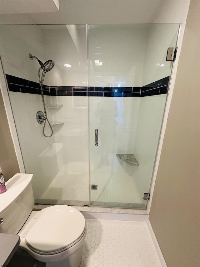 bathroom with a stall shower, toilet, and tile patterned floors