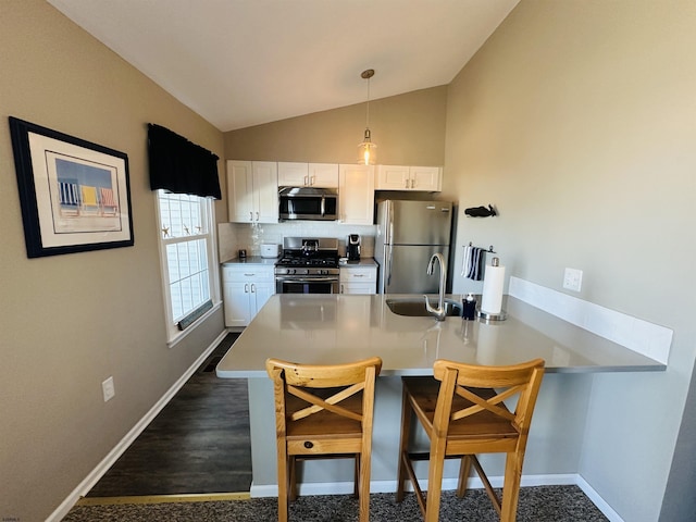 kitchen featuring a breakfast bar, a sink, white cabinets, light countertops, and appliances with stainless steel finishes