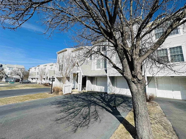 multi unit property featuring aphalt driveway, a residential view, and a garage