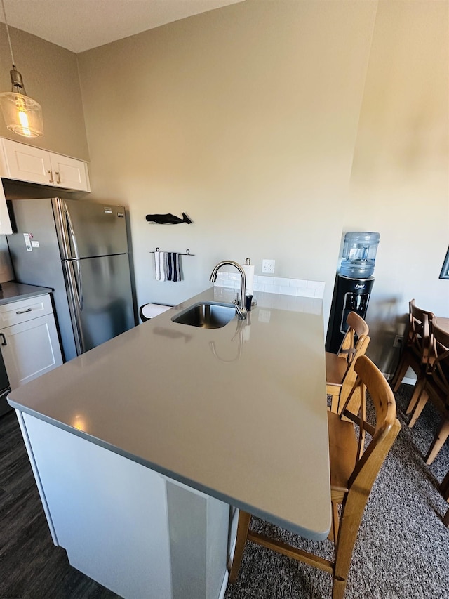 kitchen featuring a sink, white cabinetry, hanging light fixtures, freestanding refrigerator, and dark wood-style floors