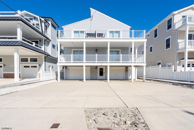 coastal inspired home with an attached garage, fence, and concrete driveway