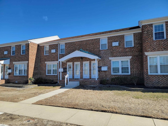 townhome / multi-family property with a front yard and brick siding