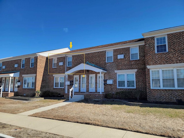 townhome / multi-family property with a front yard and brick siding