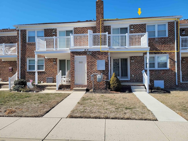 multi unit property with brick siding, a chimney, and a front yard