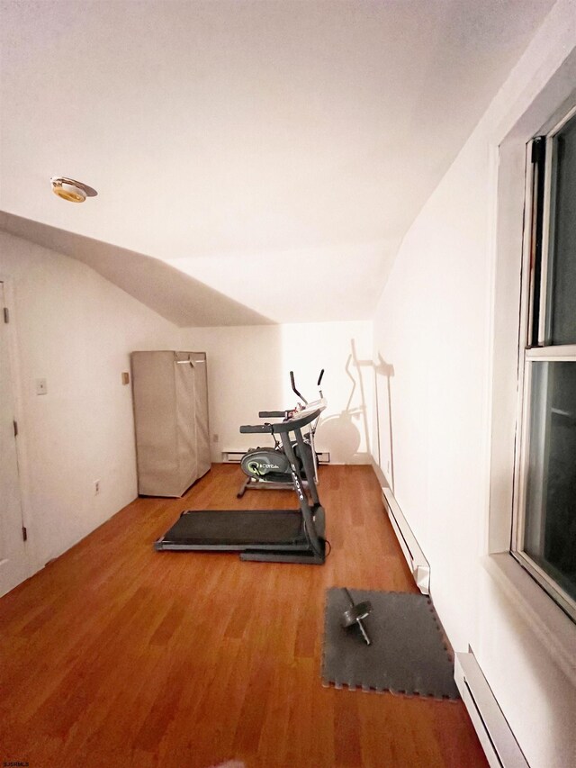 exercise area with a baseboard heating unit, lofted ceiling, and wood finished floors