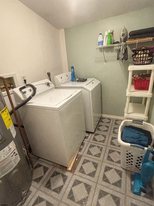 washroom featuring water heater, separate washer and dryer, laundry area, baseboards, and tile patterned floors